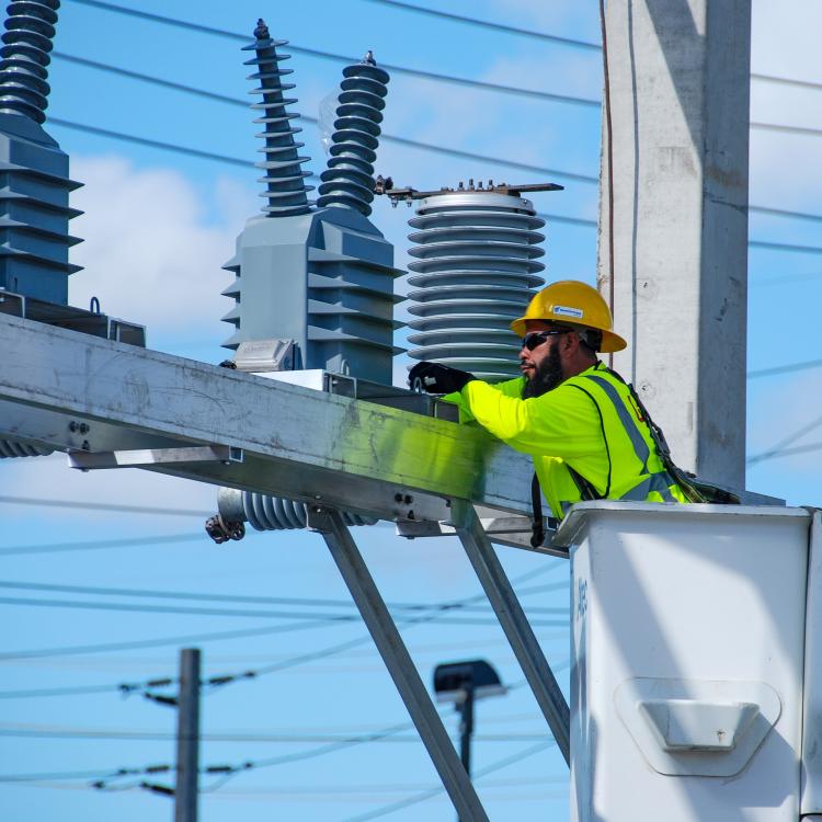 Employee in bucket truck working with transmission line