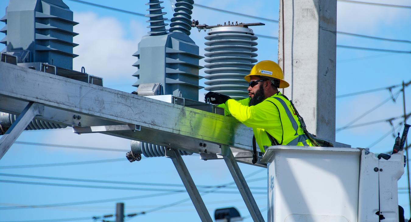 Employee in bucket truck working with transmission line